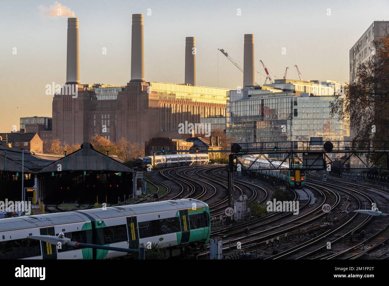 Un train part de la gare Victoria, une station électrique Battersea récemment rénovée se trouve en arrière-plan. Londres décembre 2022. Banque D'Images