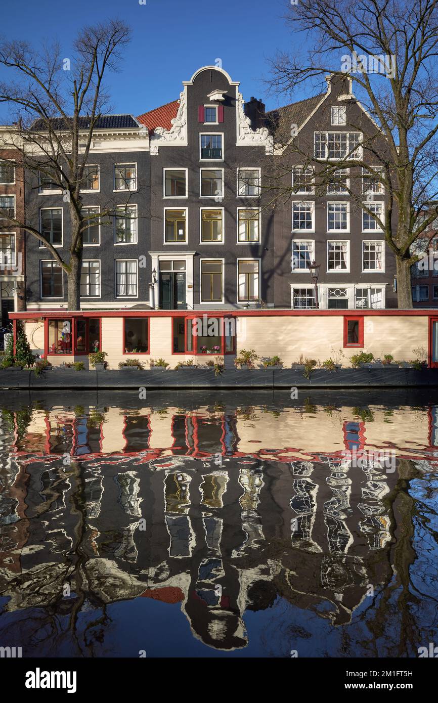 Vue vers l'est sur le canal Prinsengracht montrant une péniche amarrée devant une rangée de maisons traditionnelles d'Amsterdam. Banque D'Images