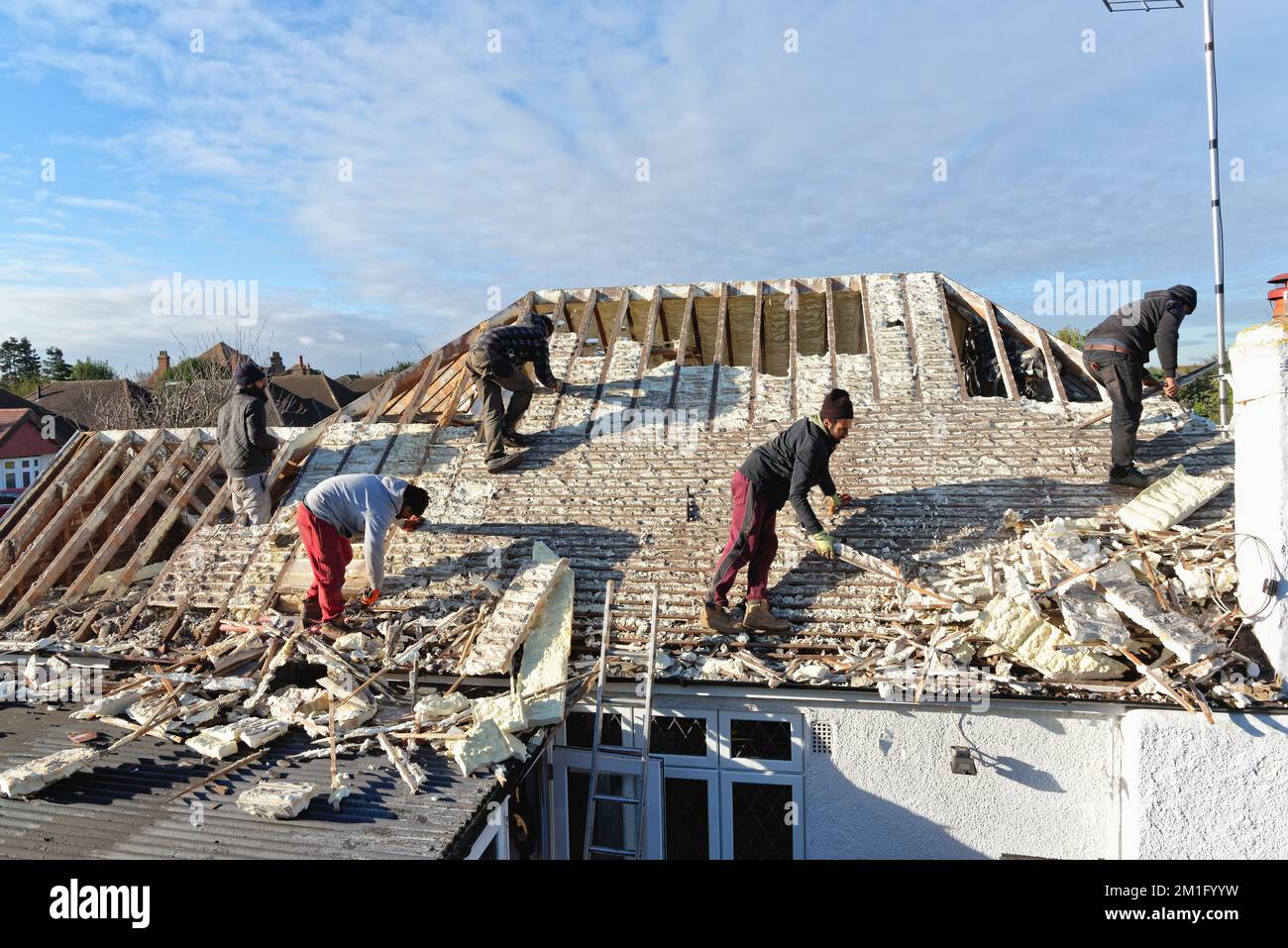 Les constructeurs retirent l'isolation en mousse pulvérisée durcie de l'espace de toit d'une maison privée de banlieue, Shepperton Surrey, Angleterre, Royaume-Uni Banque D'Images