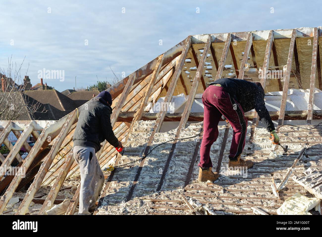 Les constructeurs retirent l'isolation en mousse pulvérisée durcie de l'espace de toit d'une maison privée de banlieue, Shepperton Surrey, Angleterre, Royaume-Uni Banque D'Images