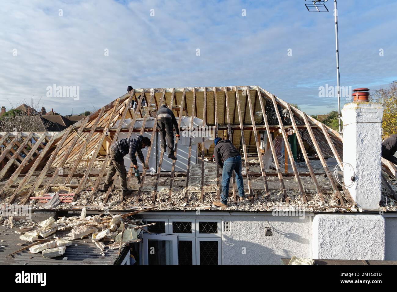 Les constructeurs retirent l'isolation en mousse pulvérisée discréditée de l'espace de toit d'une maison privée de banlieue, Shepperton Surrey, Angleterre, Royaume-Uni Banque D'Images