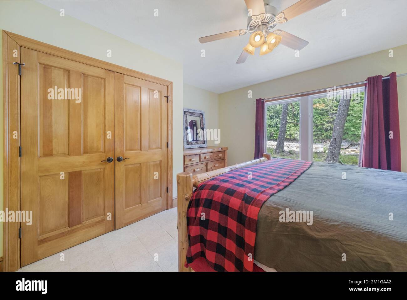 Vue intérieure d'une chambre avec ventilateur de plafond, armoire en bois et murs jaune clair. Banque D'Images