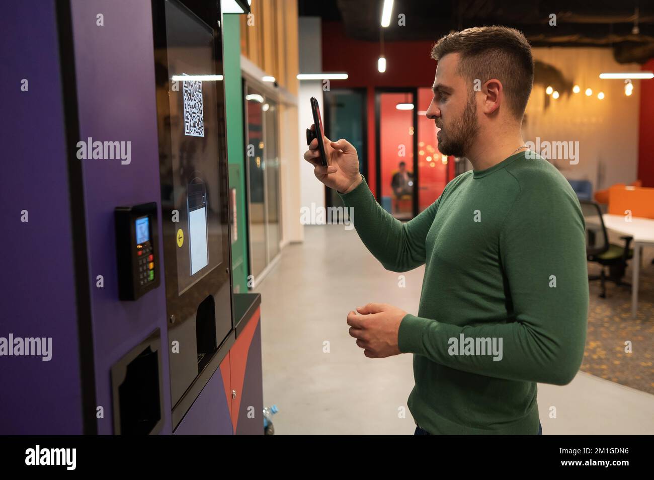L'homme caucasien paie par smartphone le café dans une machine en libre-service à l'aide du code qr. Banque D'Images L'homme caucasien paie par smartphone le café dans une machine en libre-service à l'aide du code qr. Banque D'Images