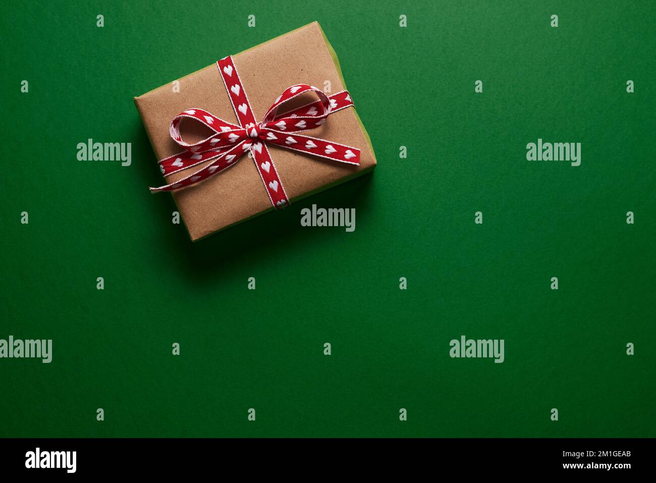 Boîte cadeau de Noël emballée dans du papier kraft sur fond vert Banque D'Images