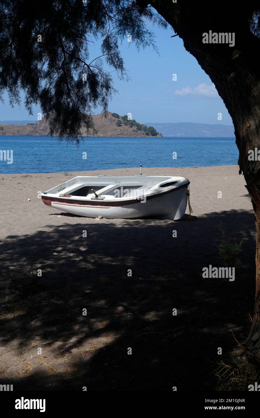 Petit bateau tiré sur le sable sur une plage déserte avec une petite île au loin, Lesbos. Septembre / octobre 2022. Banque D'Images