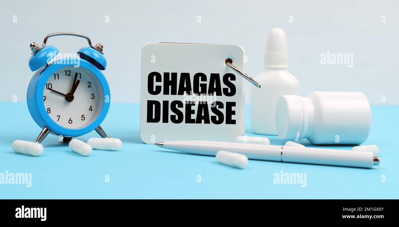 Médecine et concept de santé. Sur une surface bleue se trouvent des pilules, un réveil et un carnet avec l'inscription - maladie de Chagas Banque D'Images