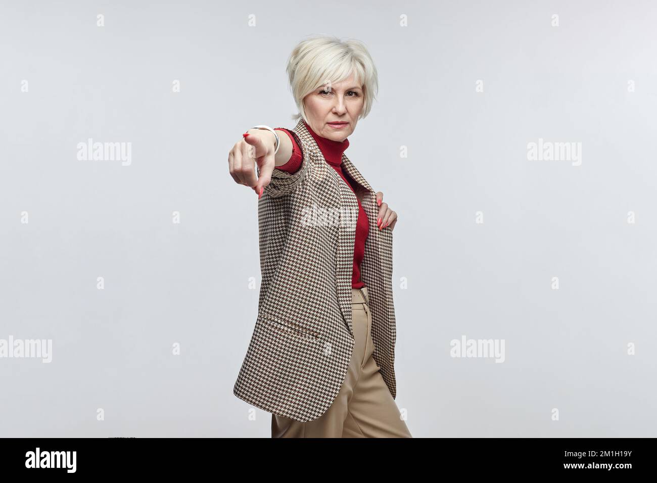 belle femme âgée avec des lunettes pointe son doigt vers l'appareil photo. le concept d'une femme d'affaires leader. Banque D'Images