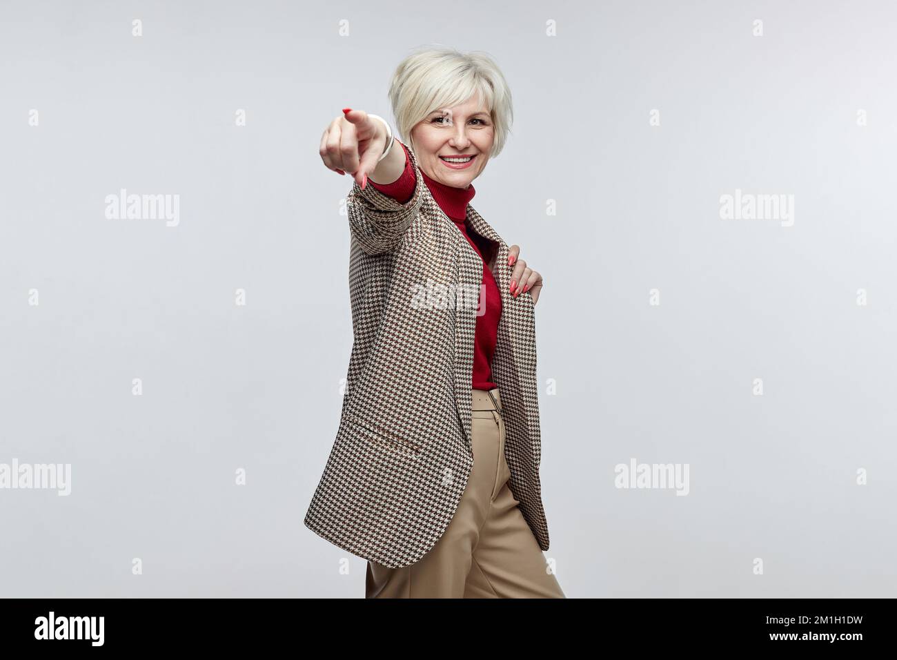 belle femme âgée avec un sourire pointe son doigt vers l'appareil photo. le concept d'une femme d'affaires leader. Banque D'Images