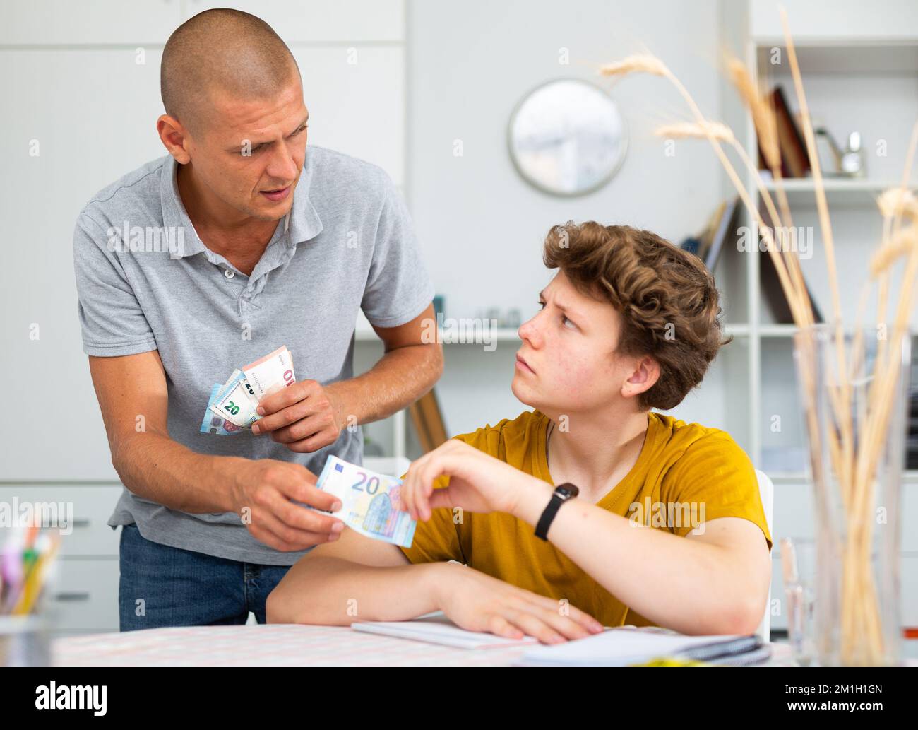 Père et fils comptant de l'argent tout en étant assis à la table à la maison Banque D'Images