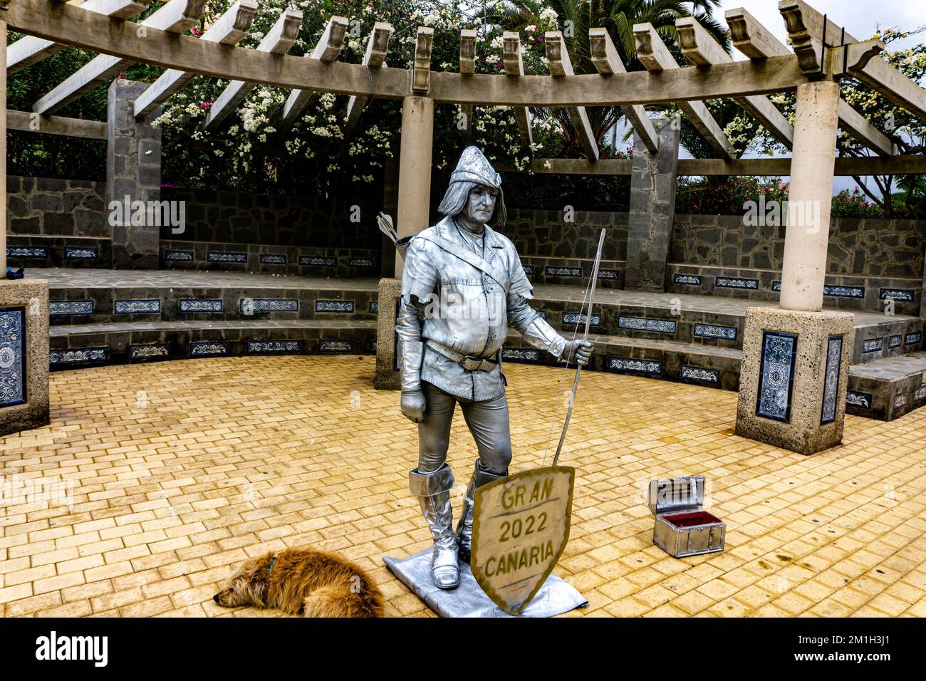 Un artiste de rue de Gran Canaria donne vie à l'histoire comme une statue vivante, habillée comme un archer avec son fidèle compagnon canin à ses côtés Banque D'Images