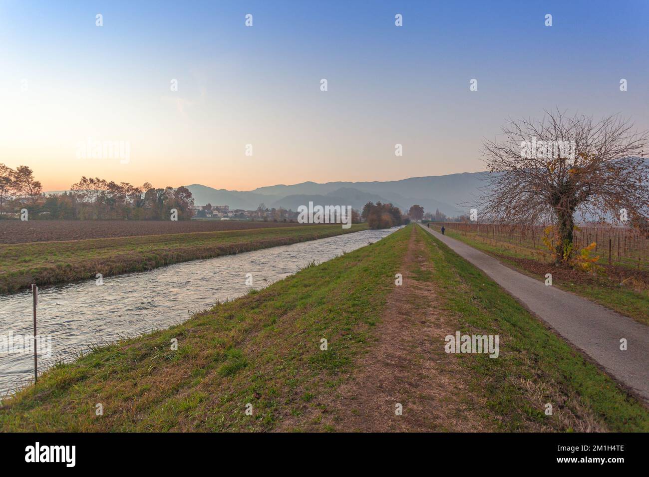 Rivière près d'une route avec des arbres colorés au coucher du soleil en automne Banque D'Images
