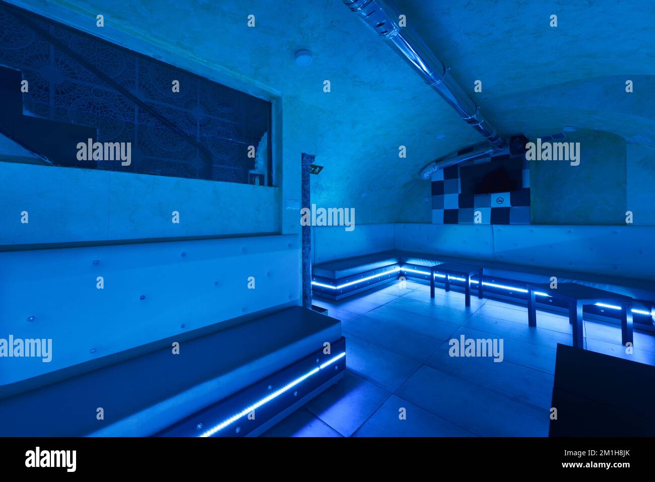 Salle de divertissement dans un lieu souterrain dans un lieu de vie nocturne avec éclairage au néon rvb et sièges blancs continus Banque D'Images