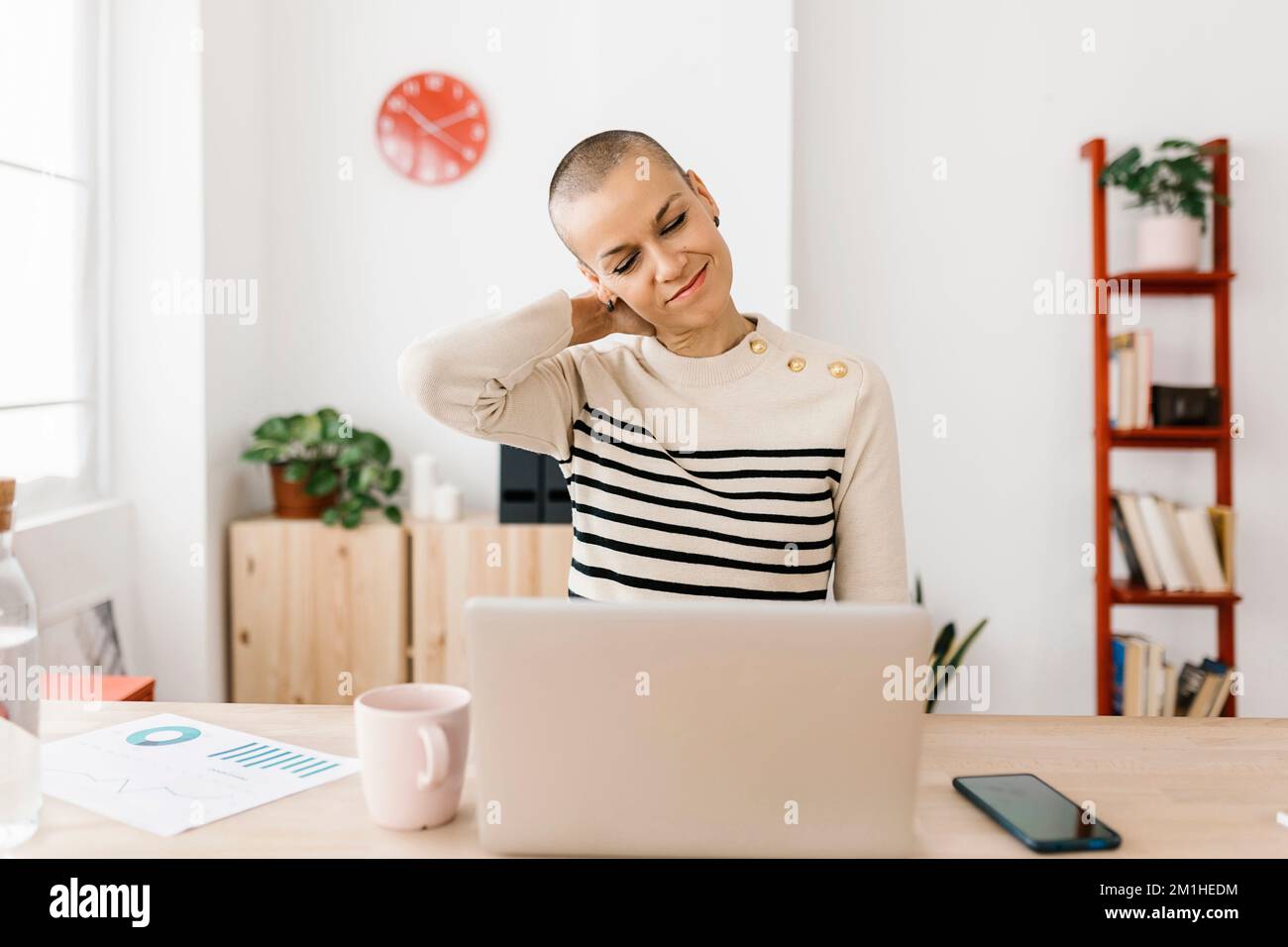 Femme d'affaires de taille moyenne s'étirant sur le lieu de travail Banque D'Images Femme d'affaires de taille moyenne s'étirant sur le lieu de travail Banque D'Images