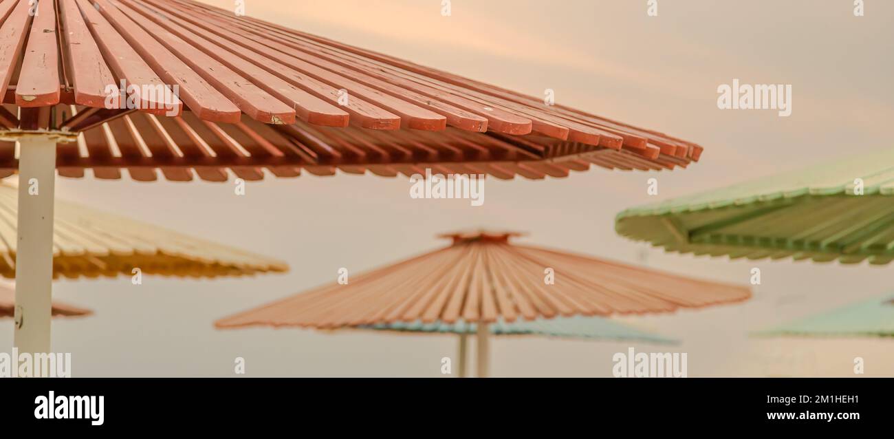 Une vue sélective de parasols en bois colorés sur la plage, au coucher du soleil, avec une vue fascinante sur un ciel de coucher de soleil en arrière-plan Banque D'Images
