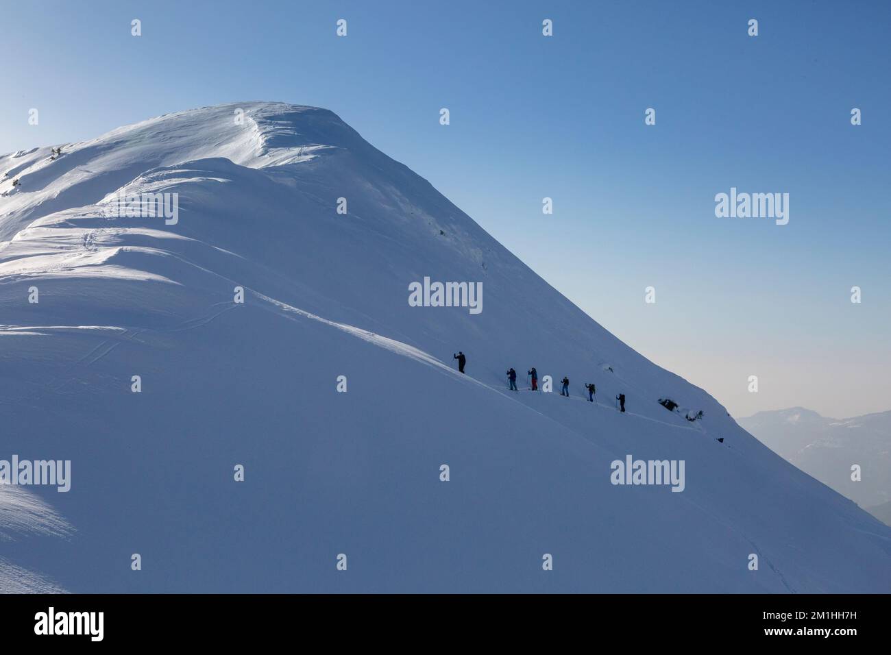 un grand groupe de touristes de ski traversent la montagne, grimpent ensemble sur une crête enneigée, les loisirs actifs dans l'arrière-pays Banque D'Images