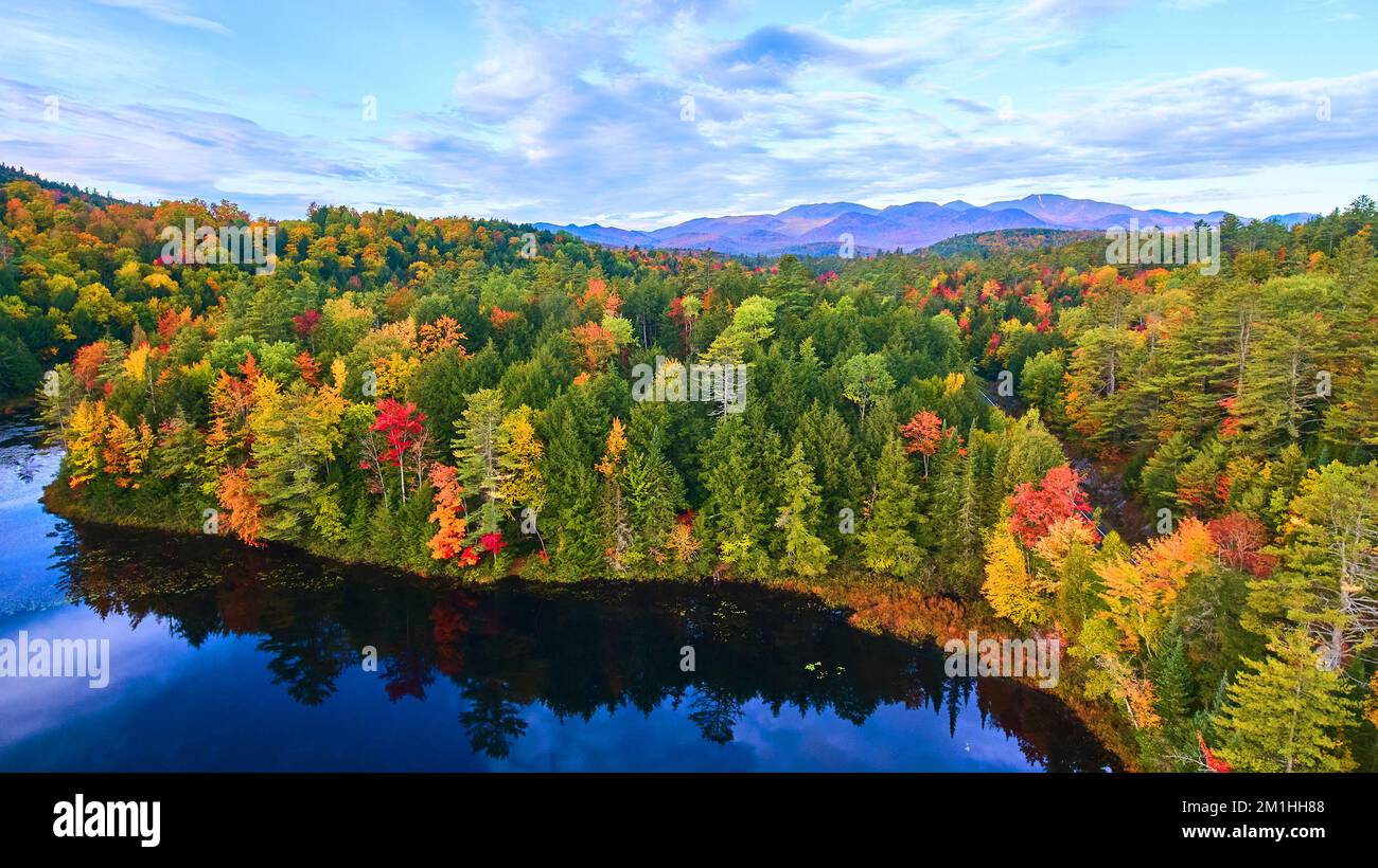 Aérien sur le lac bleu avec les collines de forêt d'automne autour et les montagnes à distance Banque D'Images
