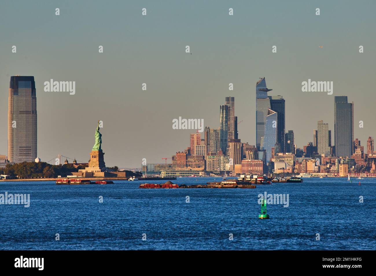 Statue de la liberté en lumière dorée depuis le ferry avec vue sur les gratte-ciel de New York Banque D'Images