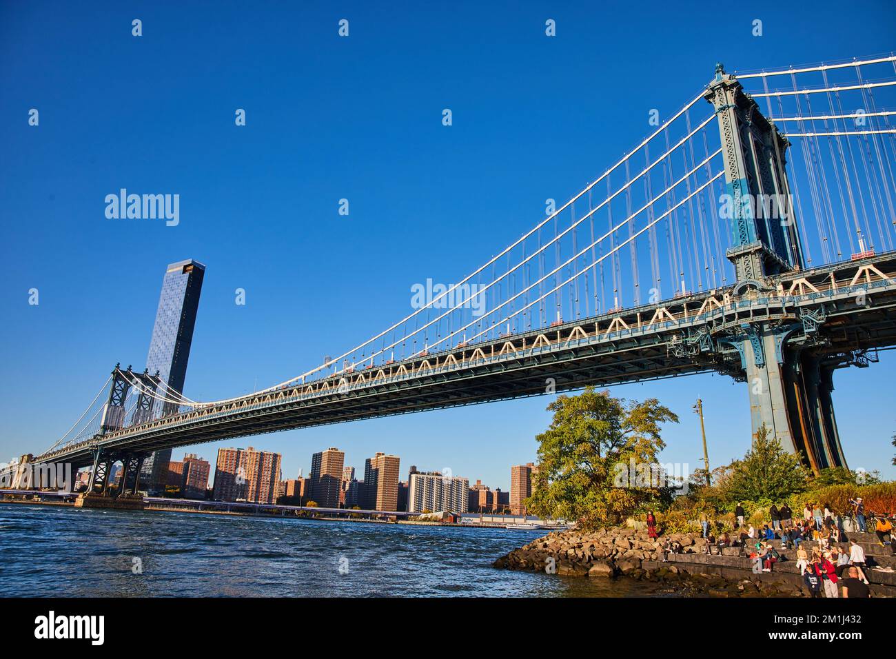 Vue de l'ensemble du pont de Brooklyn depuis un angle bas avec les eaux et la ville de New York en arrière-plan Banque D'Images
