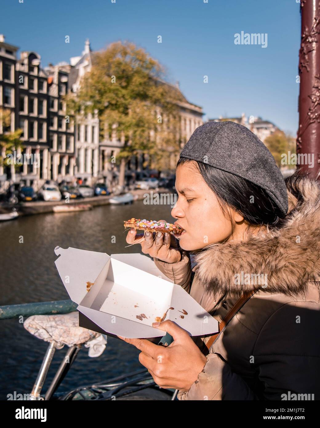 Les femmes asiatiques avec un Stroopwafel à Amsterdam est typiquement hollandaise deux pièces circulaires de gaufres remplies d'un sirop de caramel Banque D'Images