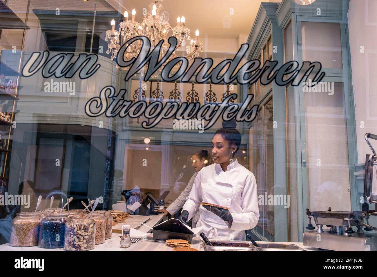 Amsterdam pays-Bas décembre 2020, femme faisant un Stroopwafel dans un magasin d'Amsterdam une cuisine typiquement hollandaise deux pièces circulaires de gaufres remplies d'un sirop de caramel Banque D'Images