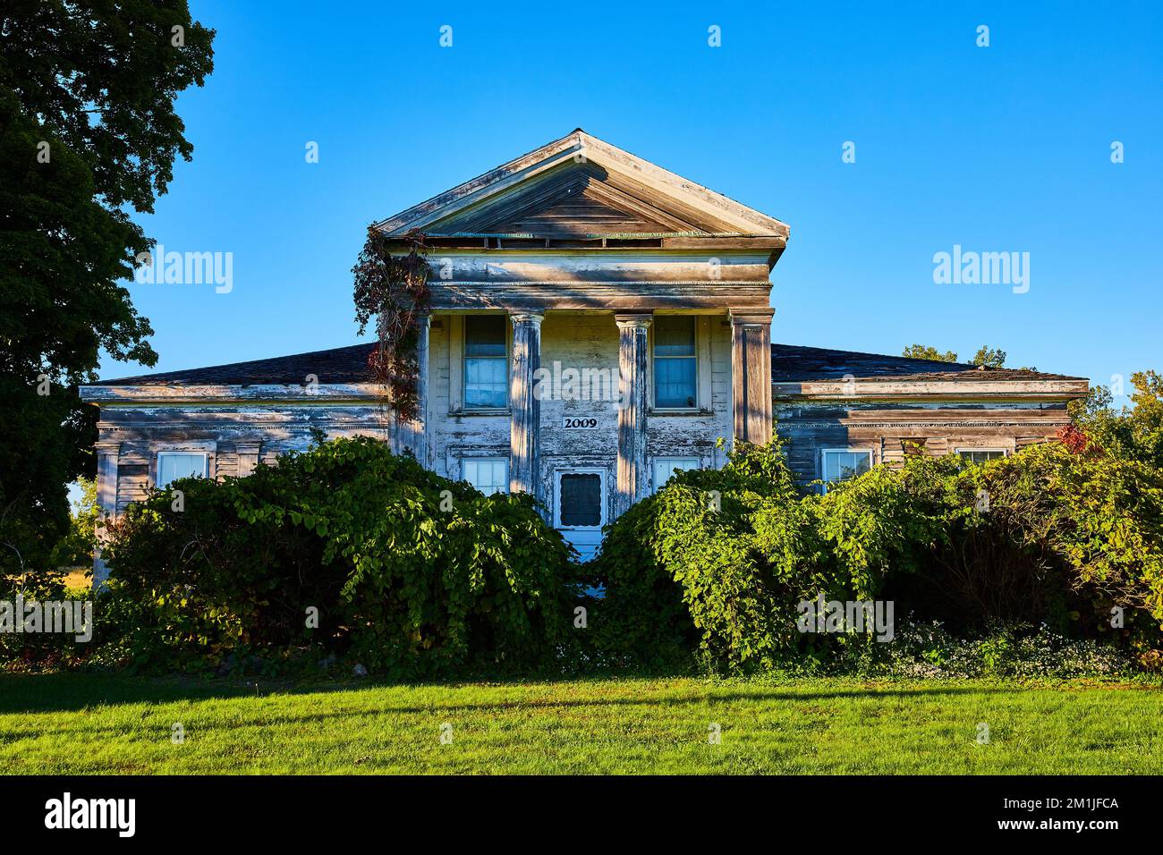 Ancienne maison de ville abandonnée avec piliers blancs et surcroissance en Amérique Banque D'Images