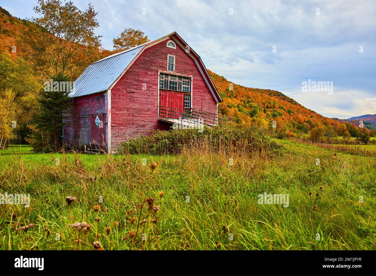 Grange rouge dans les champs de campagne entouré de montagnes de feuillage d'automne Banque D'Images