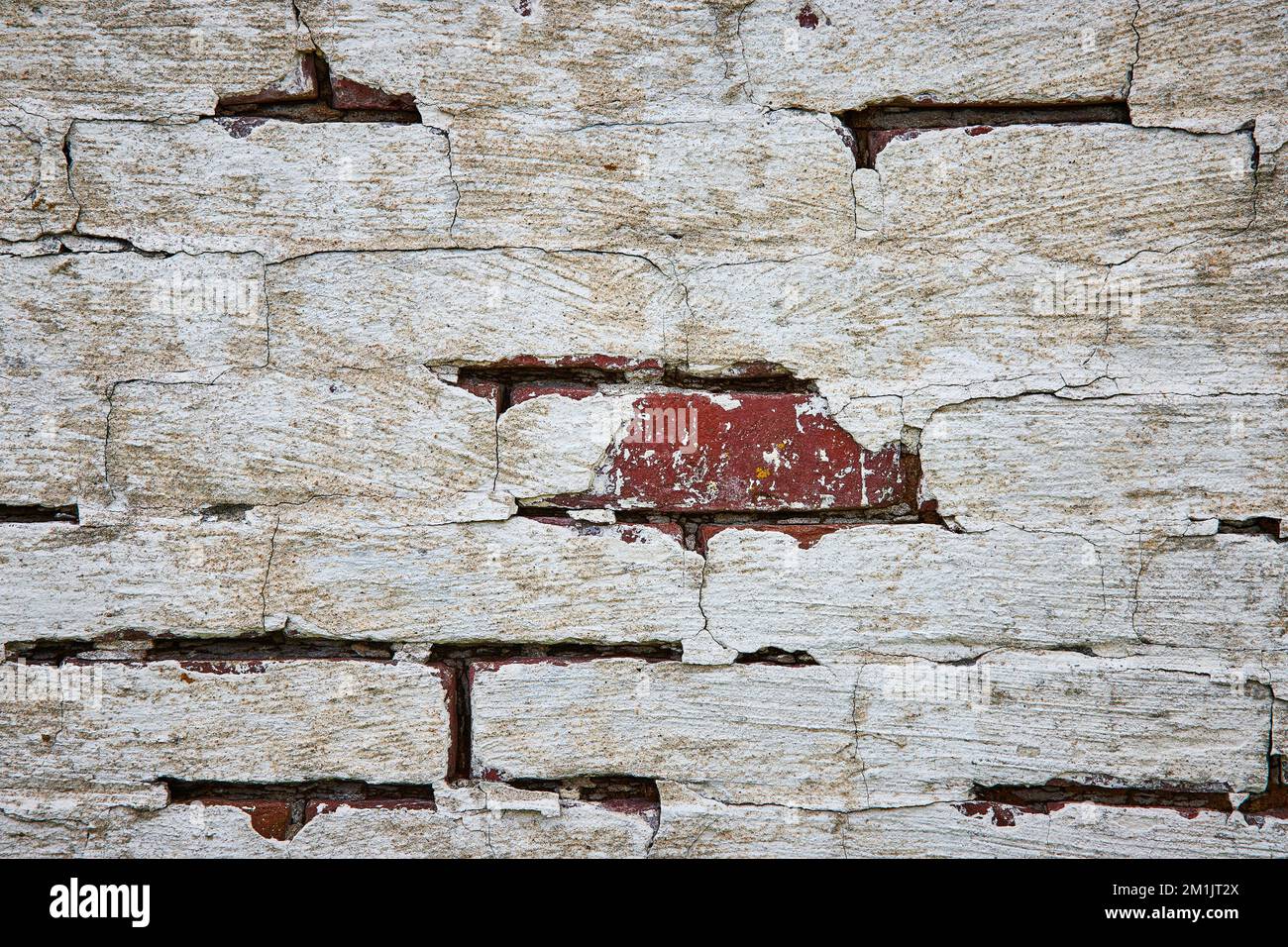 Détail du mur de briques rouges peint en blanc et en décomposition avec des fissures Banque D'Images