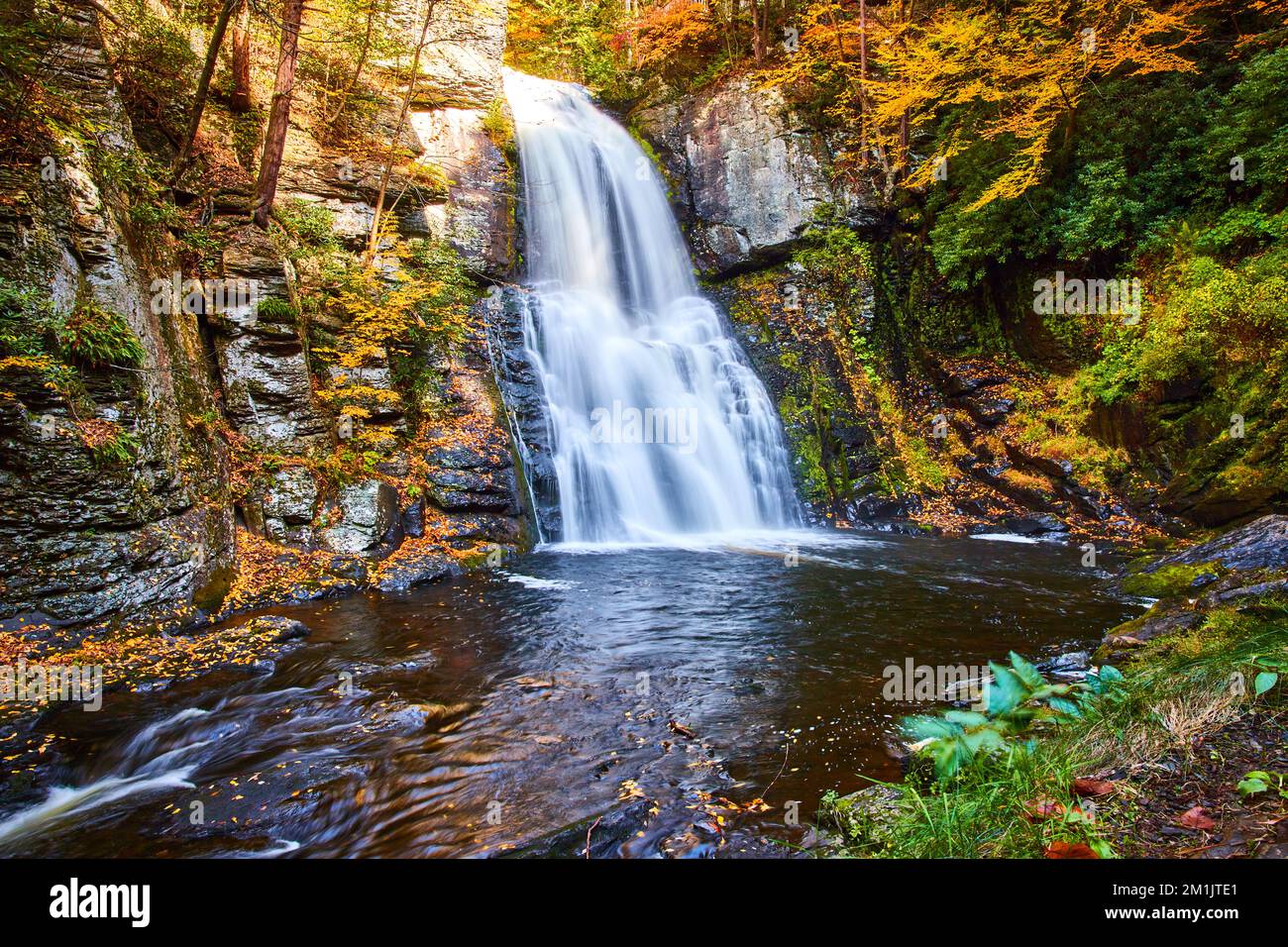 Le feuillage d'automne entoure les falaises et l'immense cascade sur les falaises au sommet de l'automne Banque D'Images