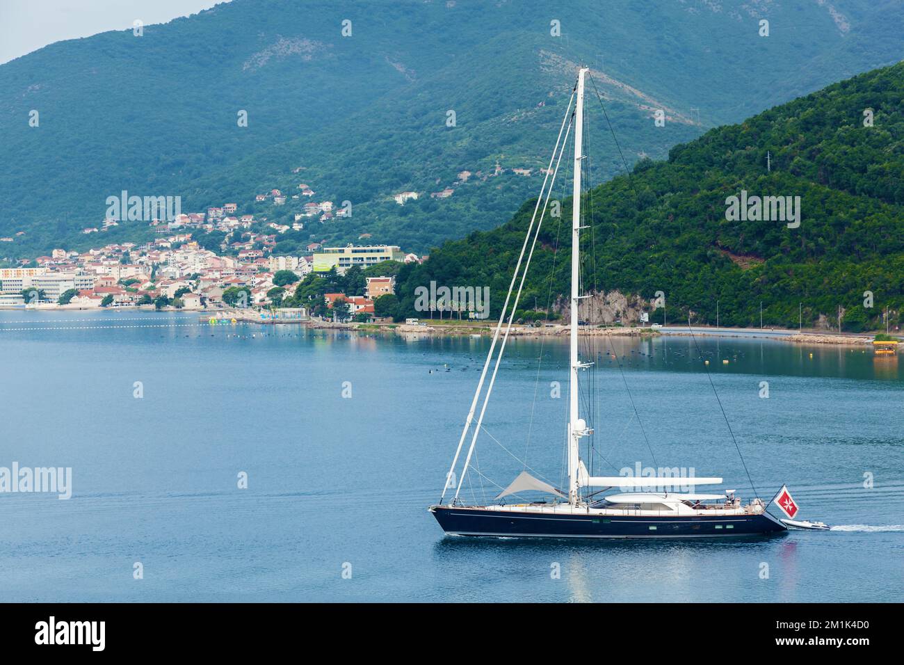 Un grand yacht à voile noir navigue le long de l'eau le long de la rive Banque D'Images