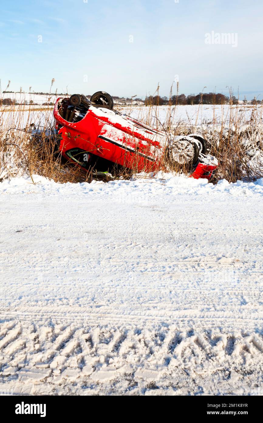 Conduite en hiver au Royaume-Uni Une voiture renversée sur une route rurale enneigée à Derbyshire, Emgland, Royaume-Uni Banque D'Images