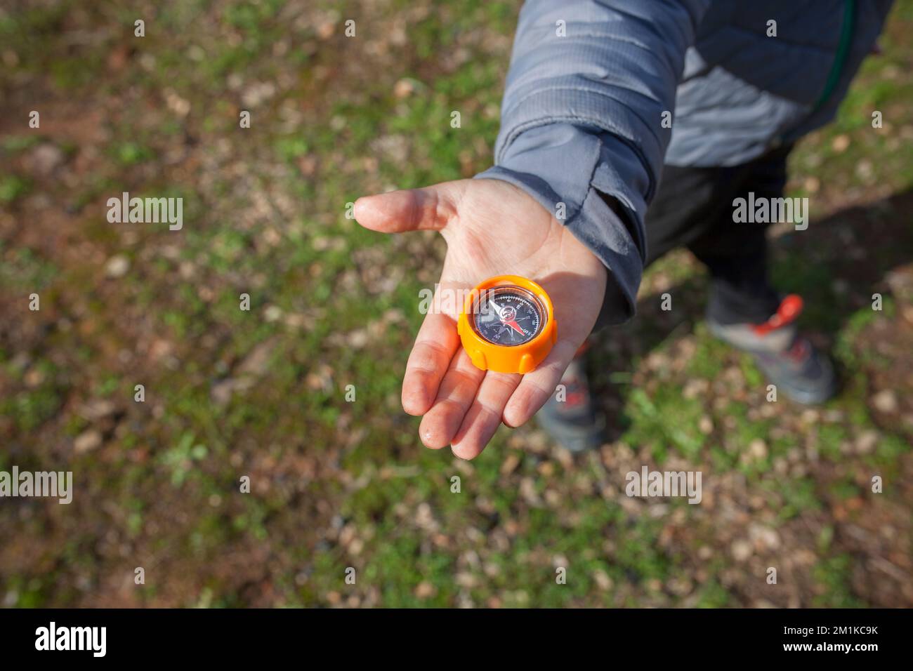 Enfant garçon tenant le compas jouet à portée de main. Jeux d'orientation dans la nature pour les enfants Banque D'Images