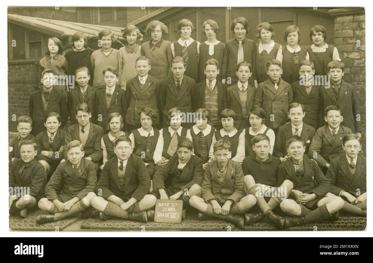 Carte postale originale des années 1920 du portrait de classe de groupe de classe de Brae Street School Grade V111 à l'extérieur dans le terrain de jeu de l'école, portant des uniformes scolaires mixtes et d'autres modes. Daté du 1927 au verso. Liverpool, Merseyside, Angleterre, Royaume-Uni Banque D'Images