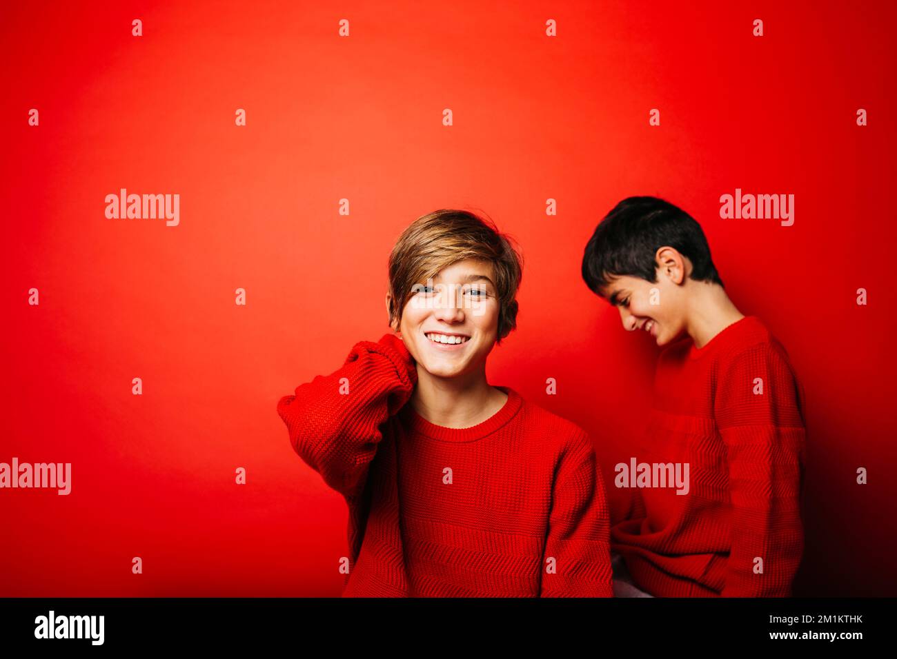 Deux pré-adolescents, portant un chandail rouge, jouant sur un fond rouge Banque D'Images