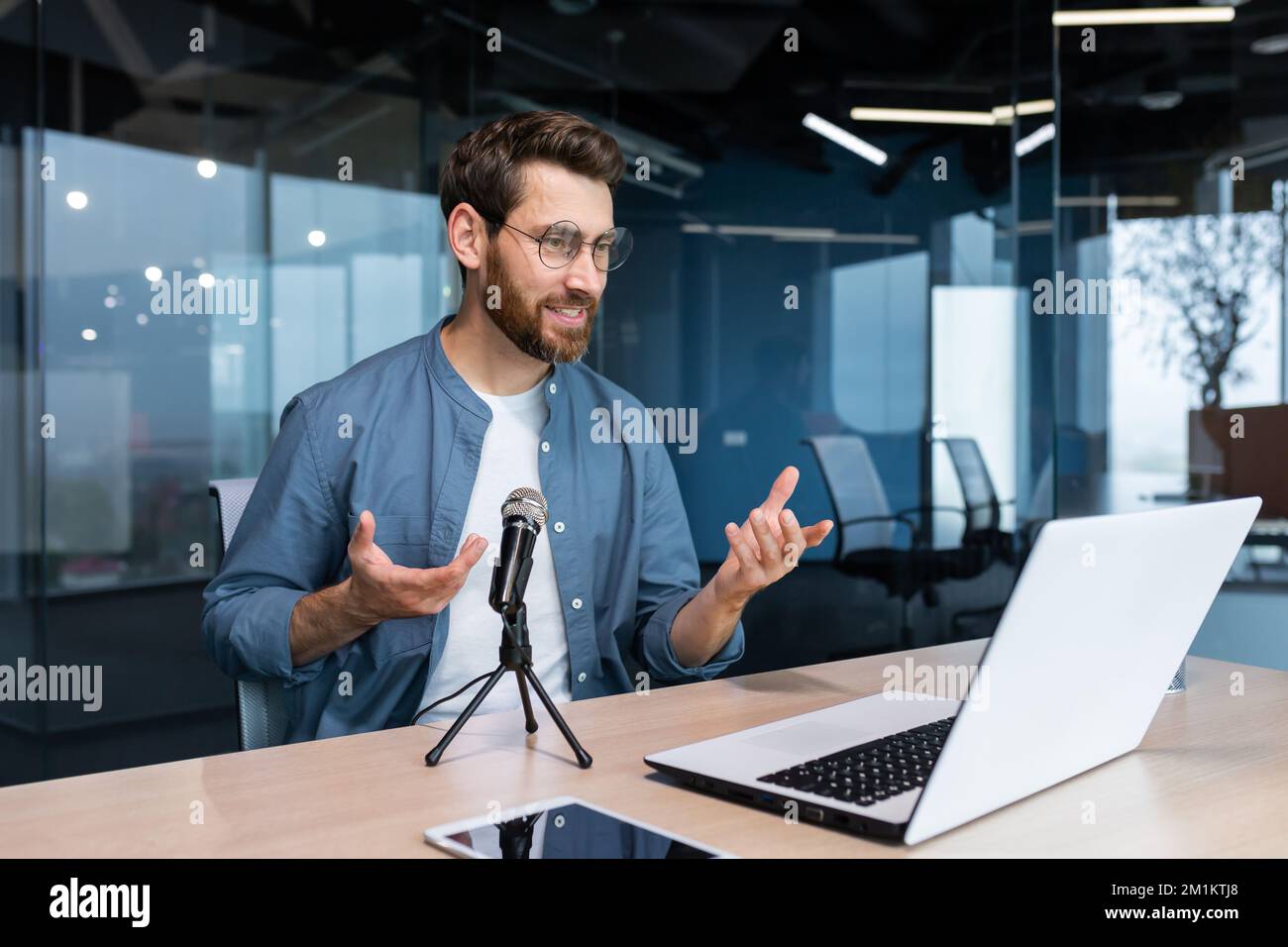 Un coach professionnel au bureau enregistre un podcast audio, un homme d'affaires travaillant sur un ordinateur portable avec un microphone professionnel et un ordinateur portable pour la radio en ligne, et un entraînement à distance. Banque D'Images