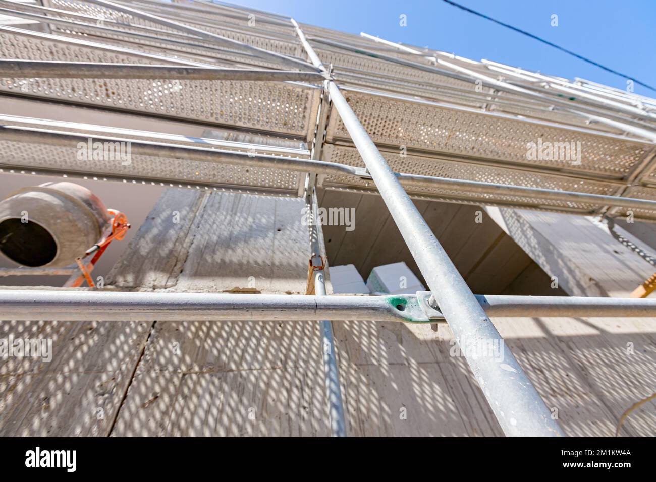 Tiré du soufflet sur un échafaudage monté à côté du bâtiment en construction, le mélangeur de ciment et les emballages de mousse de polystyrène pour l'isolation thermique sont Banque D'Images