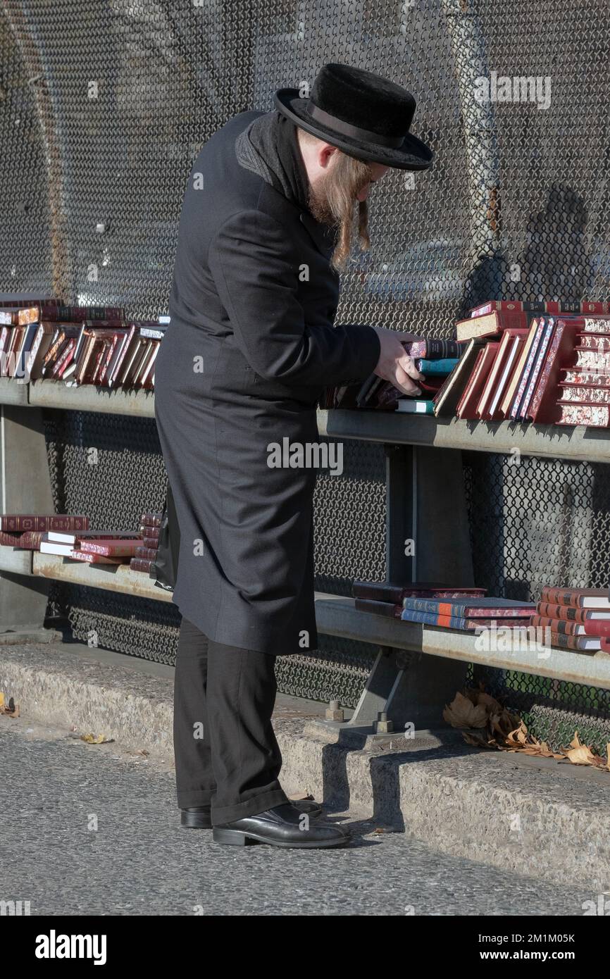 Un juif orthodoxe avec de longues boutiques de peyot à une vente de livres religieux à Brooklyn, New York. Banque D'Images