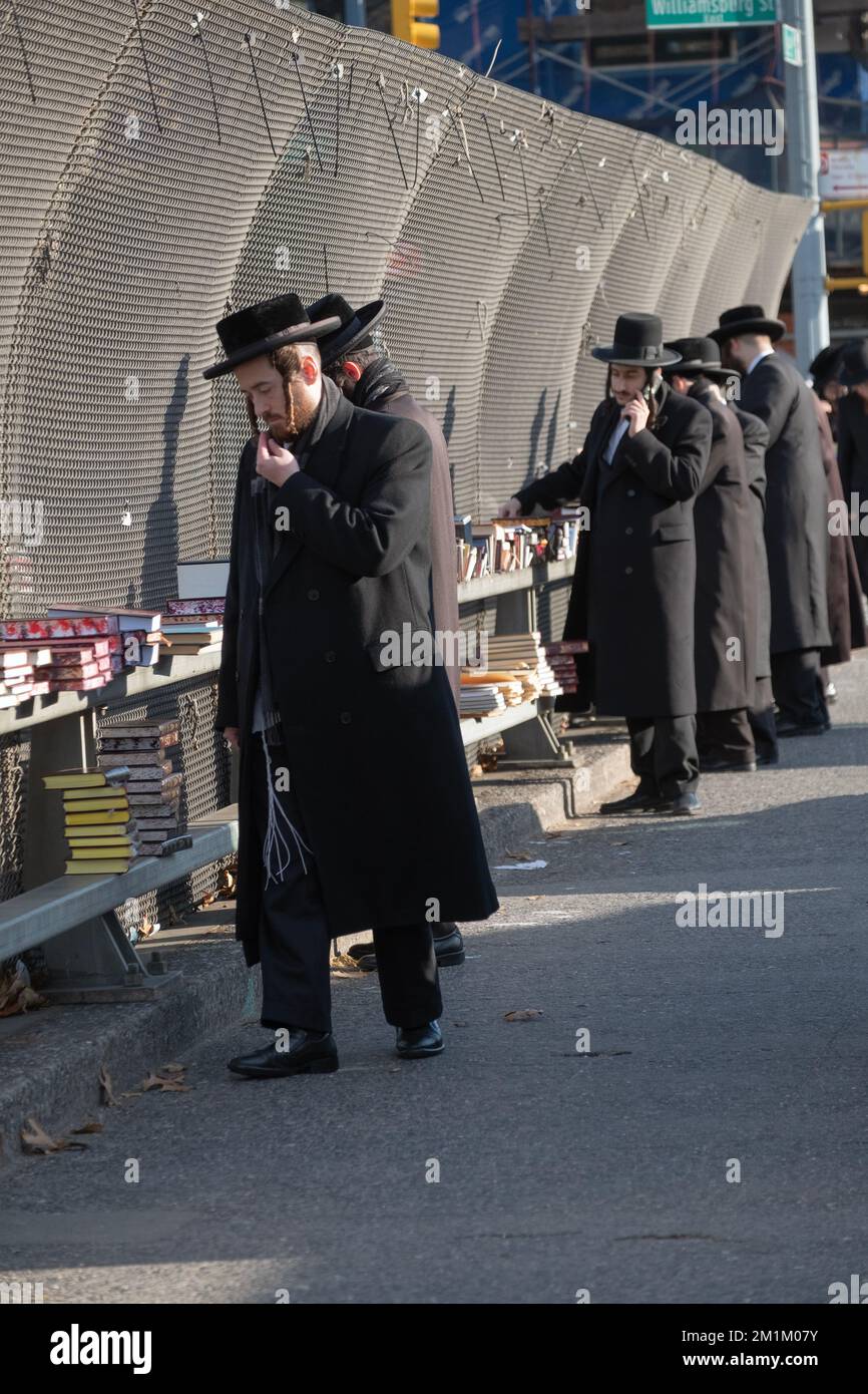 Des hommes juifs orthodoxes vêtus de livres religieux dans une boutique noire lors d'une visite en plein air à Brooklyn, New York. Banque D'Images