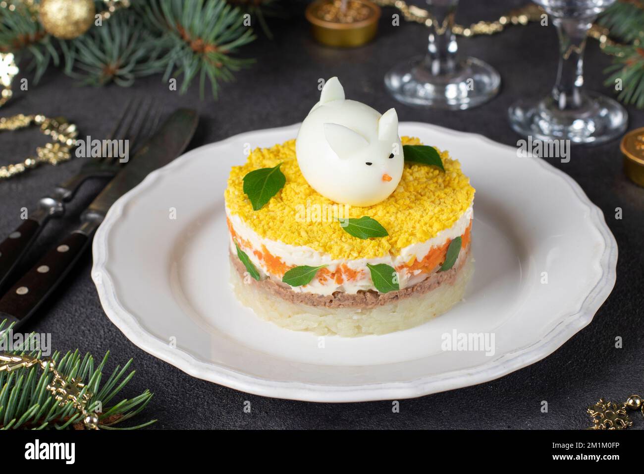 Salade de fête Mimosa pour le nouvel an avec thon en conserve, pommes de terre et carottes, lapin décoré d'œufs Banque D'Images