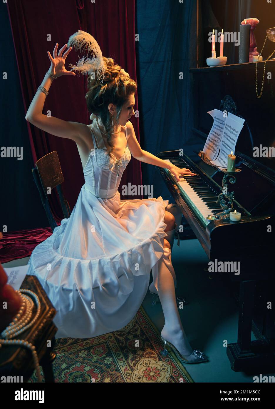 Performances émotionnellement. Portrait d'une belle jeune fille à l'image d'une princesse médiévale en robe blanche élégante assise au piano et jouant Banque D'Images
