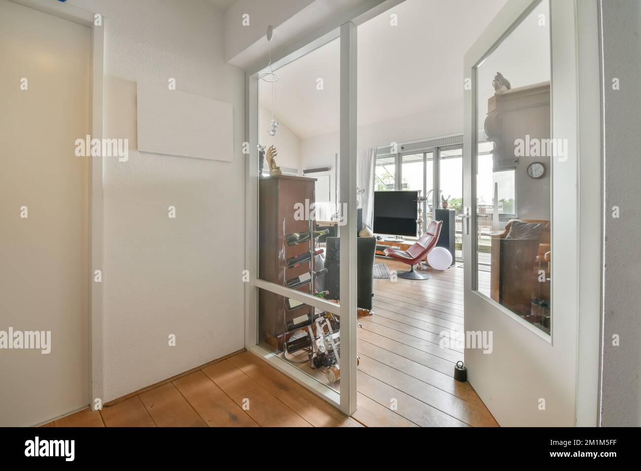 l'intérieur d'une maison avec parquet et portes vitrées coulissantes qui mènent à un patio extérieur, entouré de murs blancs Banque D'Images