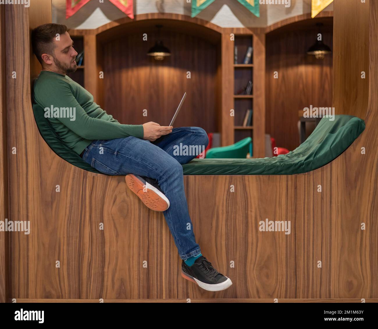 Homme barbu caucasien travaillant sur un ordinateur portable dans un collègue moderne. Banque D'Images Homme barbu caucasien travaillant sur un ordinateur portable dans un collègue moderne. Banque D'Images