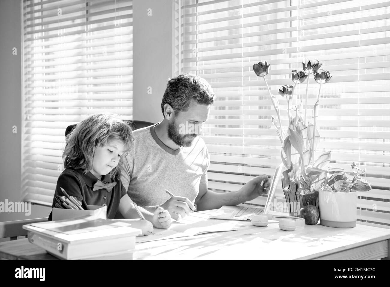 papa barbu écrivant des devoirs à l'école avec son fils garçon en classe, jour de la famille Banque D'Images