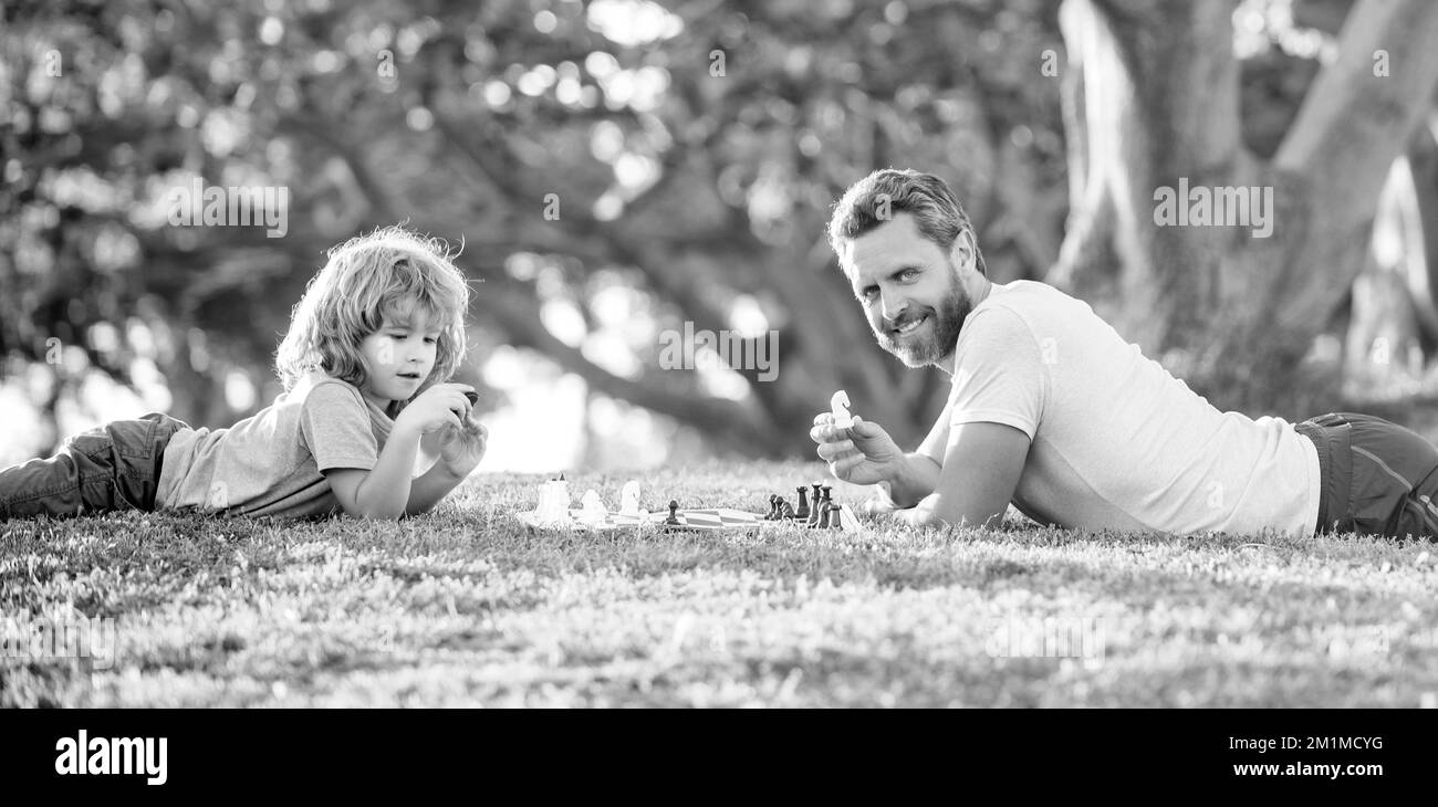 tutelles. papa et gamin jouent à la logique jeu. père et fils jouant aux échecs se détendant sur l'herbe. Banque D'Images