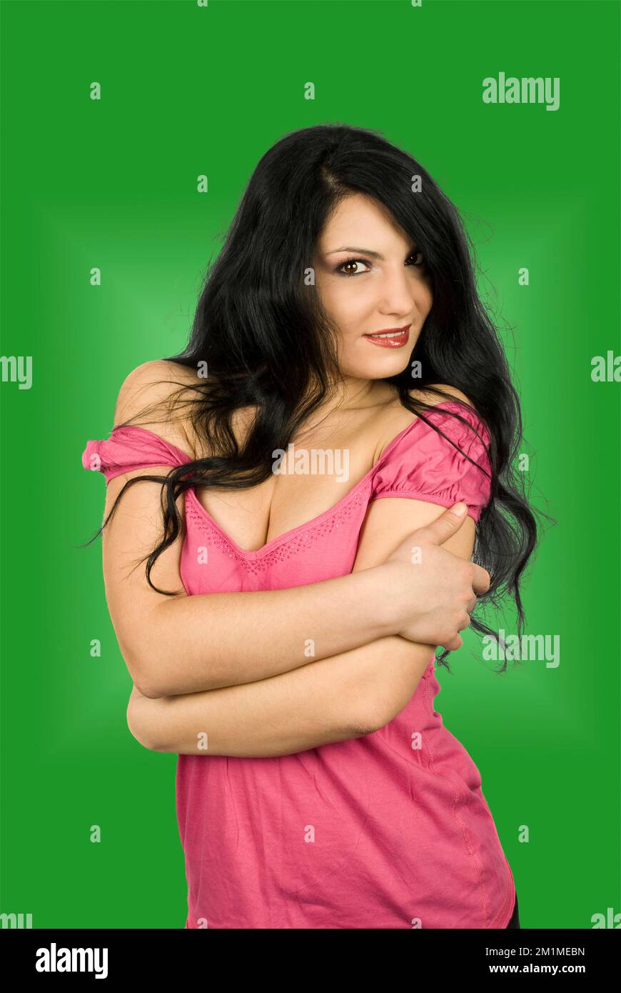 Jolie femme brune aux cheveux longs debout avec mains croisées exprimant la sensualité isolé sur fond blanc Banque D'Images