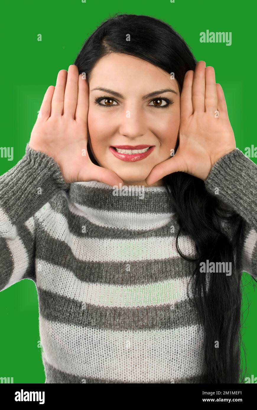 Belle femme encadrent son visage avec les mains et les doigts sont étroitement et à proximité du visage isolé sur fond blanc Banque D'Images