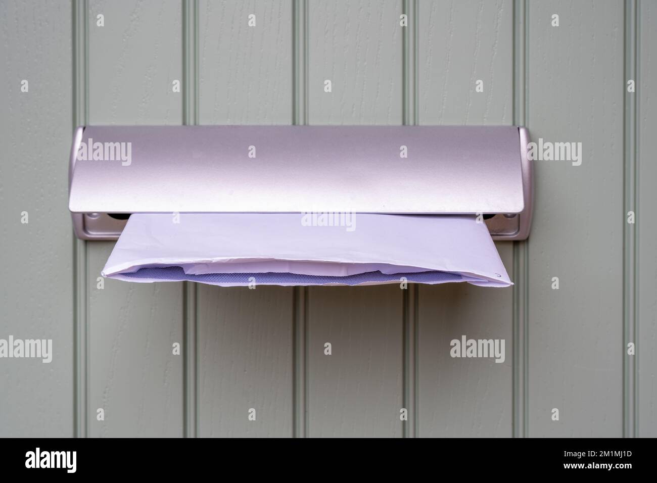 la lettre ouverte a été poussée à travers la boîte postale de la lettre d'une porte avant de la maison Banque D'Images