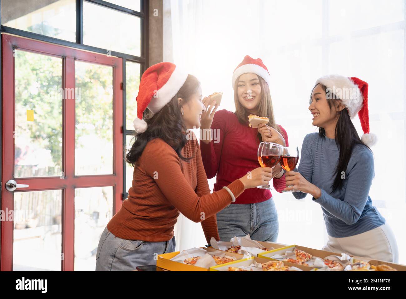 Un groupe d'amis asiatiques se réunit pour célébrer Noël avec du champagne et des pizzas à la maison. La joie des fêtes avec des amis ou un collègue concept Banque D'Images