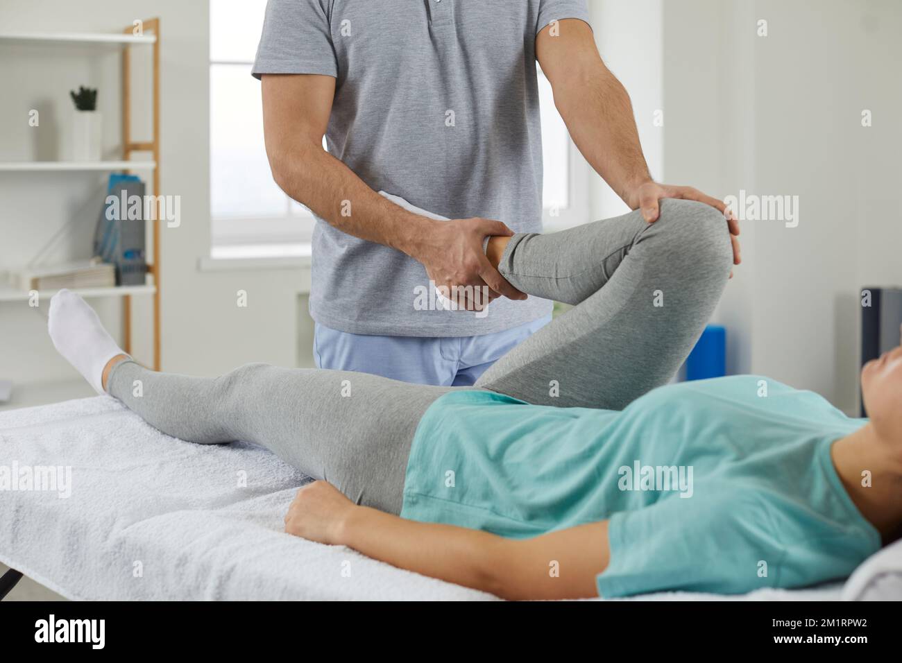 Chiropraticien professionnel, ostéopathe ou physiothérapeute examinant le genou de la jeune femme Banque D'Images
