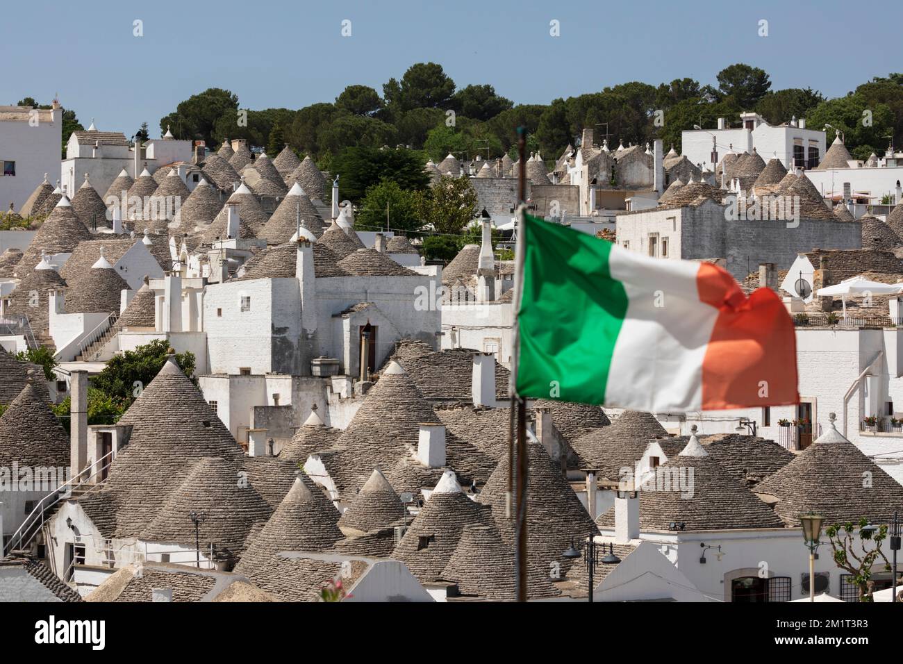 Toits coniques de maisons trulli avec drapeau italien dans la vieille ville, Alberobello, Puglia, Italie, Europe Banque D'Images