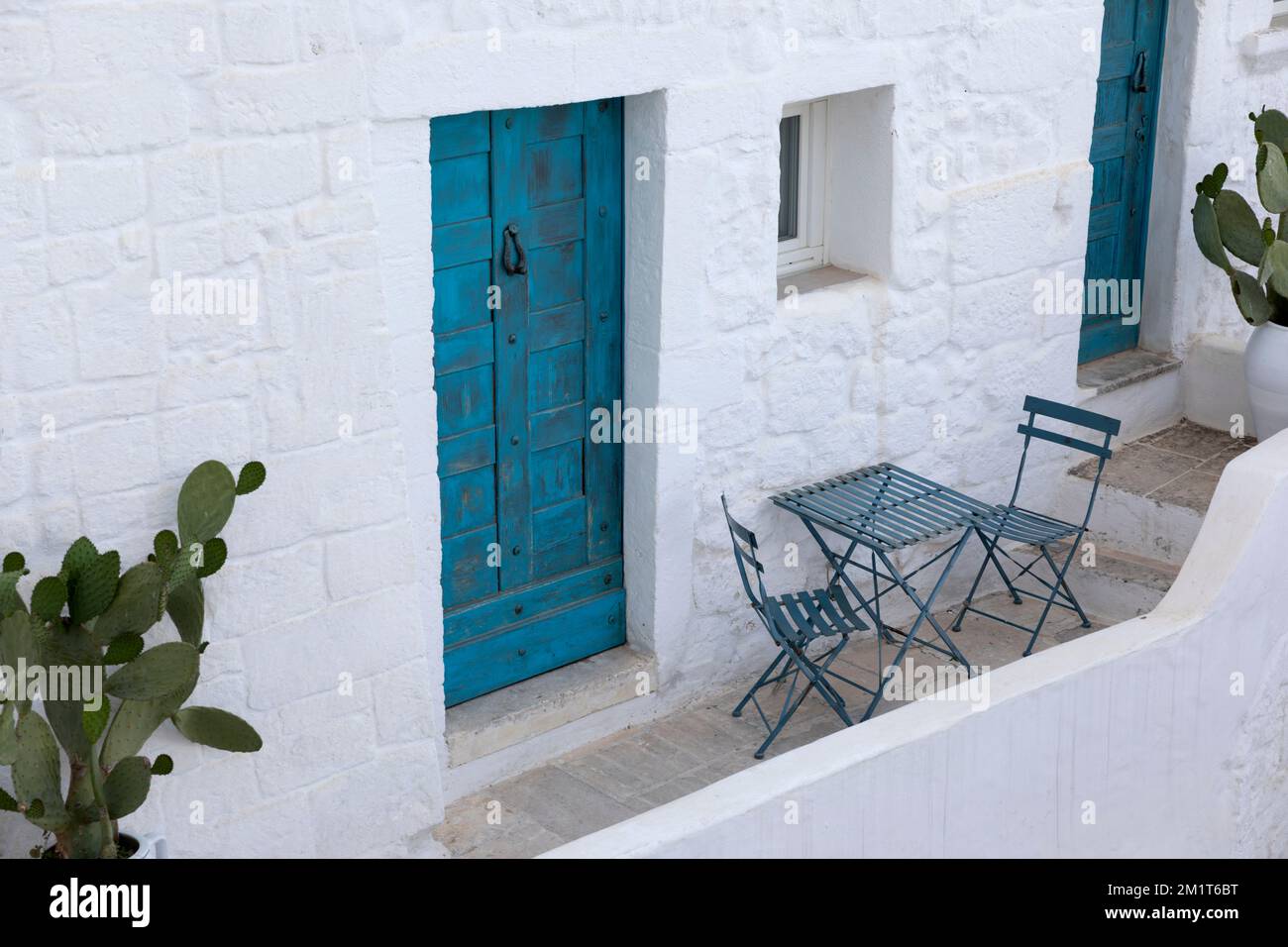 Maison blanchie à la chaux avec table et chaises sur balcon et porte bleue, Ostuni, province de Brindisi, Puglia, Italie, Europe Banque D'Images